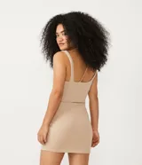 Vestido corto color beige, de canalé con tirantes anchos y recortes con repuxados.