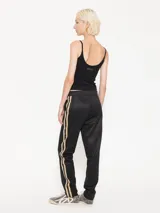 Pantalón de tela de punto color negro, con cintura elastizada y cintas rayadas en los laterales.