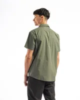 Camisa de manga corta color beige, confeccionada en 100% algodón, con cuello clásico, cierre frontal con botones y bolsillo en el pecho.