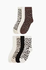 Pack de siete pares de medias de caña media, con diseños variados: dos pares lisos en color crema y blanco, un par negro liso, y cuatro pares con estampado de leopardo en diferentes combinaciones de colores.