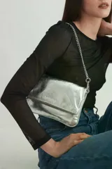 Bandolera plateada de cuero con solapa frontal y correa combinada de cuero y cadena metálica. Incluye una correa desmontable y regulable en cuero con eslabones metálicos.