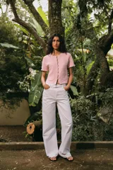 Chaqueta de punto color crema con cuello redondo, manga corta con volantes, bolsillos de plastrón y cierre frontal con botones metálicos.