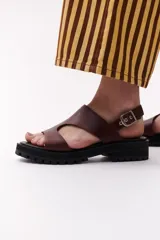 Sandalias marrones de cuero con suela track negra y hebilla plateada.