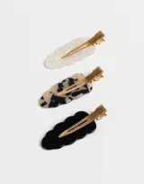 Set de tres hebillas para el pelo con forma ondulada. Incluye una hebilla blanca nacarada, una hebilla carey y una hebilla negra.