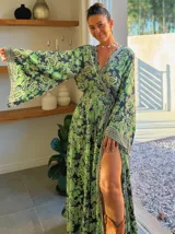 Kimono largo de seda con estampado floral en tonos verde, marrón y beige. Tiene mangas amplias y corte cruzado con lazo ajustable en la cintura.
