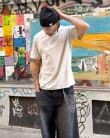 Remera color crema de corte clásico con cuello redondo y estampado en la espalda de una huella digital con forma de pelota de fútbol y el logo de Umbro.