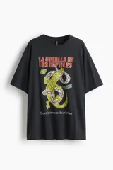 Remera negra de algodón con corte amplio, cuello redondo y mangas cortas. Estampado frontal con un cocodrilo y una serpiente entrelazados, texto en español e inglés.