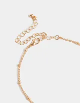 Collar corto dorado de triple cadena con dijes de corazones y perlas sintéticas.