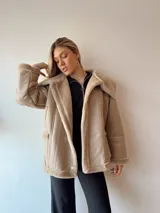 Campera gamulan color beige con interior de piel sintética, cuello solapa y cierre con botones a presión.