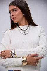 Sweater de punto color crudo con cuello redondo, diseño de ochos y mangas largas.