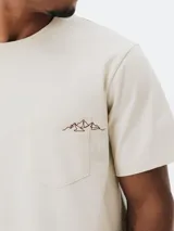 Remera color beige de algodón con bolsillo en el pecho y bordado de montañas.