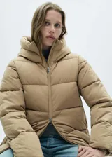 Campera puffer color beige con capucha, cierre frontal con cremallera y bolsillos laterales con cremallera.