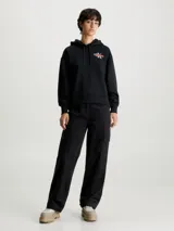 Buzo negro de corte relaxed, con capucha ajustable con cordón, puños y bajo acanalados. Presenta un logo de Calvin Klein Jeans estampado en el pecho.