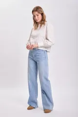 Blusa color crudo con cuello redondo, mangas largas abullonadas y detalle de plisado y encaje en el frente.