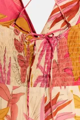 Vestido midi con estampado de hojas en tonos rosados, amarillos y marrones. Escote en pico con tirantes finos cruzados en la espalda. Detalle de nudo en el delantero y cierre lateral con cremallera oculta.