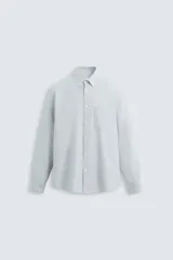 Camisa celeste a rayas verticales, de corte regular fit, confeccionada en tejido de algodón. Tiene cuello abotonado, manga larga con puños abotonados, bolsillo de parche en el pecho y cierre frontal con botones.