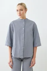 Camisa de jean a rayas verticales azules y blancas, con cuello mao y mangas largas.