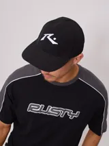 Gorra negra con logo Rusty bordado en blanco.