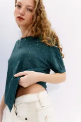 Remera verde esmeralda de lino con tachas termofijadas al tono en el delantero.