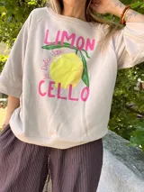 Buzo color crema con mangas cortas, cuello redondo y estampado de un limón con la frase "Limoncello La Dolce Vita" en color rosa.