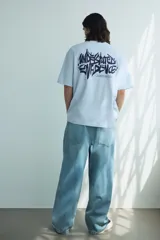 Remera de punto de algodón color celeste claro, con cuello redondo y hombros caídos. Presenta un pequeño estampado en tipografía graffiti azul oscuro en el pecho.