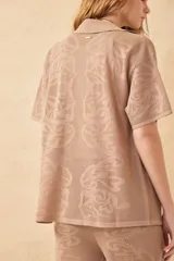 Camisa negra de tejido calado, con cuello clásico, manga corta y cierre frontal con botones.