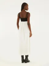 Vestido midi con tirantes finos, corte debajo del busto y falda amplia. La parte superior es negra y la falda es blanca.