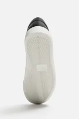 Zapatillas blancas de cuero sintético con cordones, forro interior y plantilla color beige.