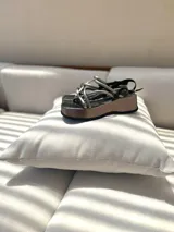 Sandalias negras con tiras entrecruzadas y suela plana, diseñadas para brindar comodidad y seguridad.