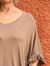 Buzo holgado color marrón, con escote en V ribeteado con brillo sutil y mangas cortas con volados en los puños.