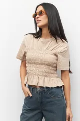 Remera negra de algodón con cuello redondo y mangas cortas. Presenta fruncidos en la cintura.