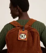 Tag de valija marrón y amarillo con forma rectangular y correa negra. Estampa de la plataforma 9 3/4 de Hogwarts.