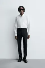 Camisa de algodón color celeste claro, corte regular fit, con cuello abotonado (button-down), manga larga con puño abotonado y bolsillo de parche en el pecho izquierdo.