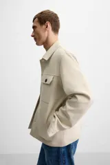 Sobrecamisa color beige de corte recto, con cuello solapa, manga larga con puños abotonados, cierre frontal abotonado, bolsillos de parche con solapa en el pecho y bolsillos de ojal en la cadera.