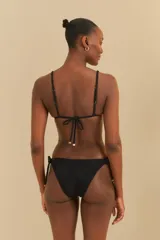 Conjunto de bikini negro con textura, compuesto por un corpiño triangular con tirantes finos ajustables y una bombacha con lazos laterales.