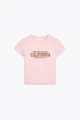 Camiseta rosa de algodón y modal, corte slim fit, cuello redondo, manga corta y largo crop. Estampado frontal con la frase "Old Sacramento CALIFORNIA UNITED STATES, EST. 1974" en color marrón.