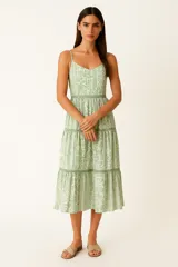 Vestido midi evasé con estampado floral en tonos verde y blanco, breteles finos y escote en pico.