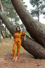 Mono color ocre de gabardina 100% algodón, con corte clásico, cierre frontal completo, pantalón largo con bolsillos, manga corta y cintura fruncida en la espalda.