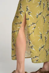 Falda midi color verde oliva con estampado de ramas y hojas en tonos grises y blancos. Tiene cintura elastizada con cordón ajustable y un tajo lateral.