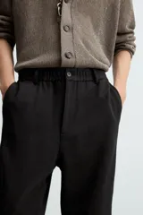 Pantalón de vestir color blanco hueso, de corte recto y tiro medio, con cintura elástica y cierre frontal de botón y cremallera. Presenta bolsillos frontales y bolsillos traseros de vivo.