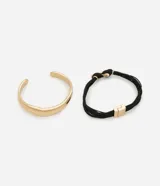 Set de dos pulseras: una rígida abierta color dorado y otra de hilos negros con cierre y detalle central dorado.