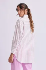 Camisa oversize blanca con rayas verticales rosas, de manga larga con puños abotonados, cuello clásico y bolsillo de parche en el pecho.