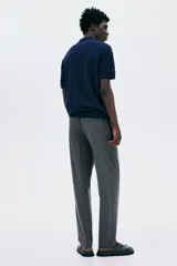 Pantalón jogger de vestir gris oscuro, corte slim fit, con cintura elástica ajustable con cordón, bolsillos laterales y traseros. Presenta pliegues delanteros y traseros.