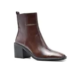 Botas de cuero negro con caña media, punta cuadrada y taco geométrico. Presentan un tirador trasero y elástico lateral para facilitar el calce.
