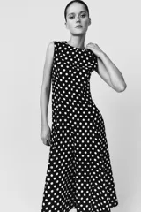 Vestido midi negro con estampado de lunares blancos, cuello redondo y sin mangas.