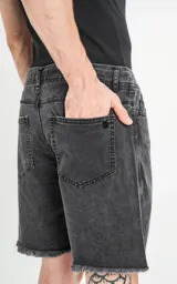 Bermuda de denim rígido, color negro lavado (acid wash), de cinco bolsillos y corte regular, con ruedo desflecado.