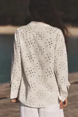 Camisa color crudo con bordados florales perforados y detalles engomados, de corte recto, cuello solapa y manga larga.