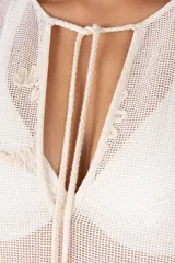 Kaftán largo de algodón traslúcido color blanco marfil, con bordados en tono beige claro en el frente y en los bordes. Presenta un escote en V con cordones terminados en borlas.