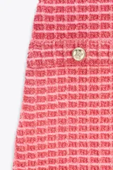 Vestido corto color crema confeccionado en tejido elástico con textura. Tiene escote redondo, tirantes anchos y falsos bolsillos de vivo con botón dorado en el delantero.