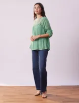 Blusa verde agua de gasa con cuello redondo y aplique de crochet. Tiene mangas 3/4 amplias con puño y botón, y forro interno a tono.